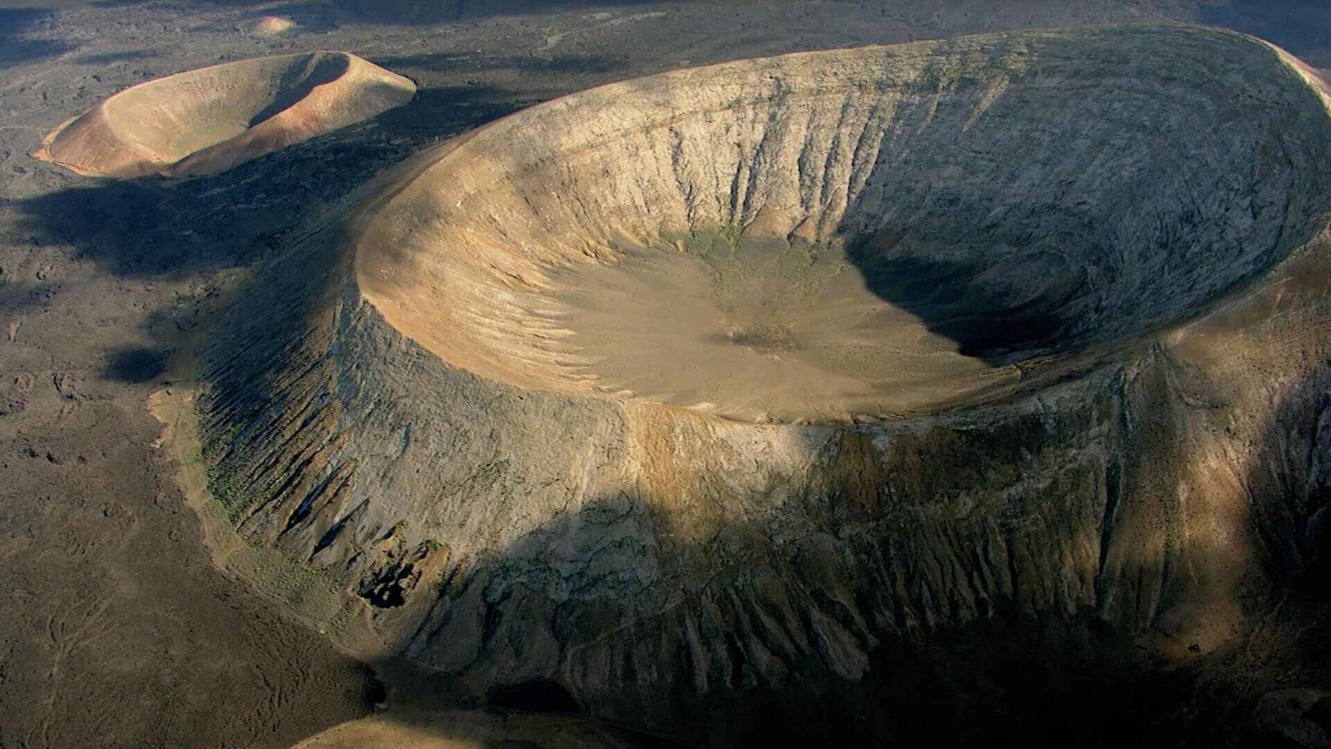 Vista aérea de la Caldera Blanca en Lanzarote, un amplio cráter volcánico rodeado de paisaje árido.