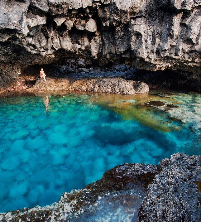 Charco Azul de El Hierro, uma lagoa natural de águas turquesas rodeada de rocha vulcânica sob uma falésia.